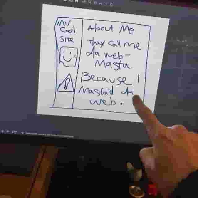 Simon points at his computer screen, which shows a paint mockup of a very basic two column site layout with some childish looking filler text. The left column says My Cool Site, followed by a box with a smily face, then a warning sign. The main column on the right says About Me - They call me the web master because I mastered the web. Everything is misspelled, pixelated, and miscoloured with excessive jpeg compression.